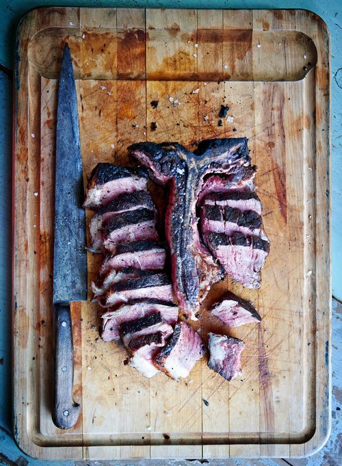 A color photograph of a steak and a knife on a cutting board.