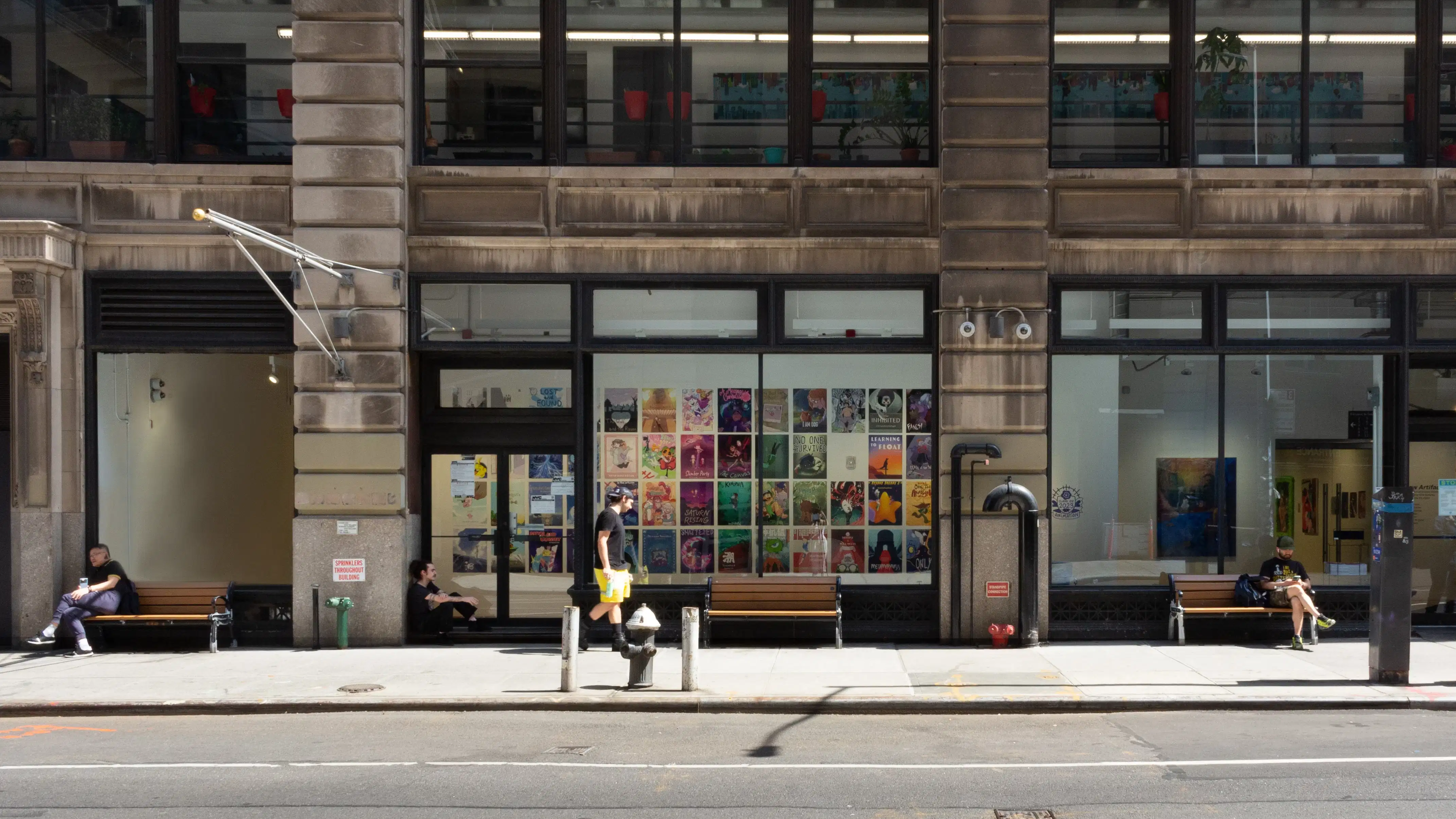 Street view of large windows with posters lining a hallway inside.
