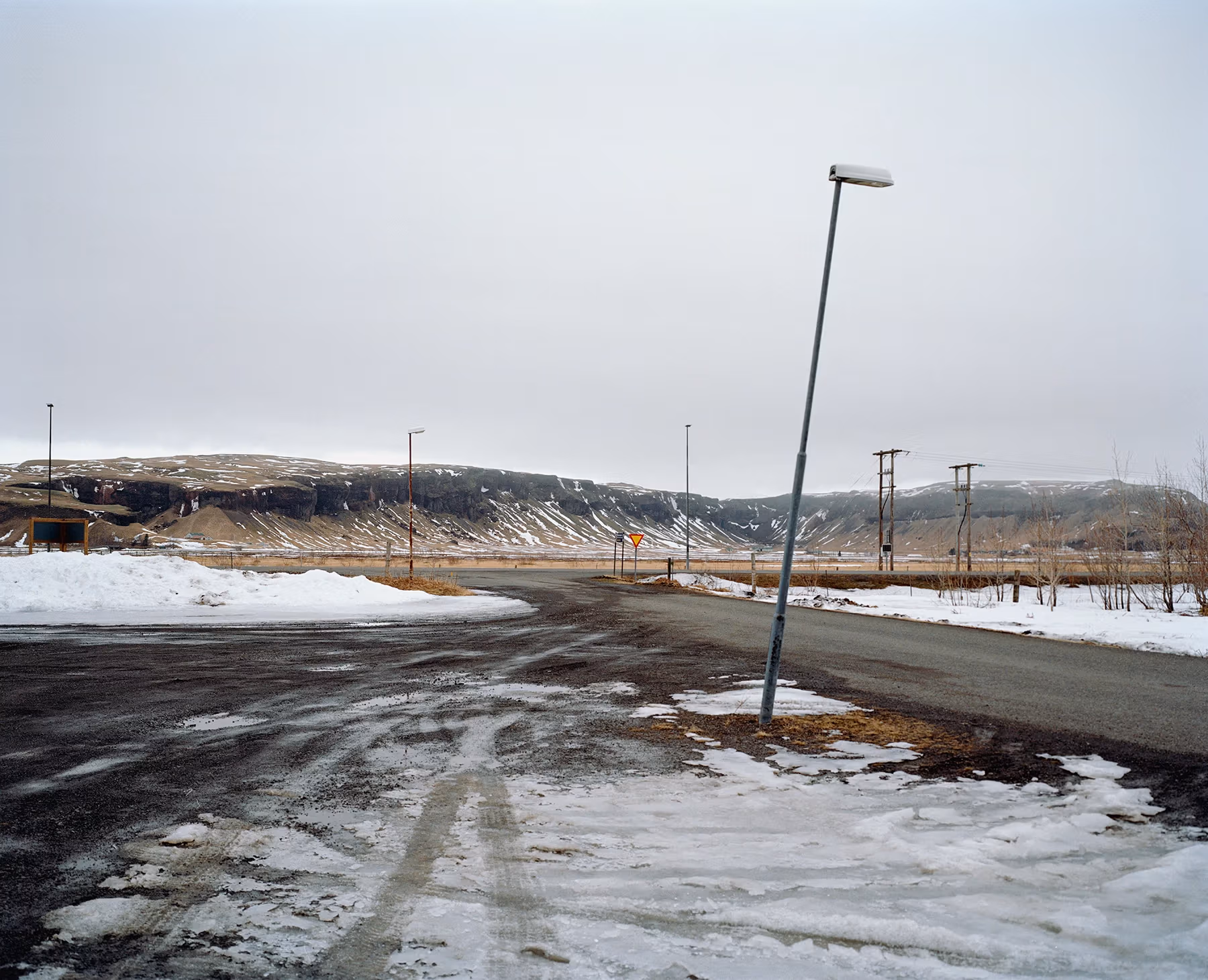 A snowy road with mountains in the background.