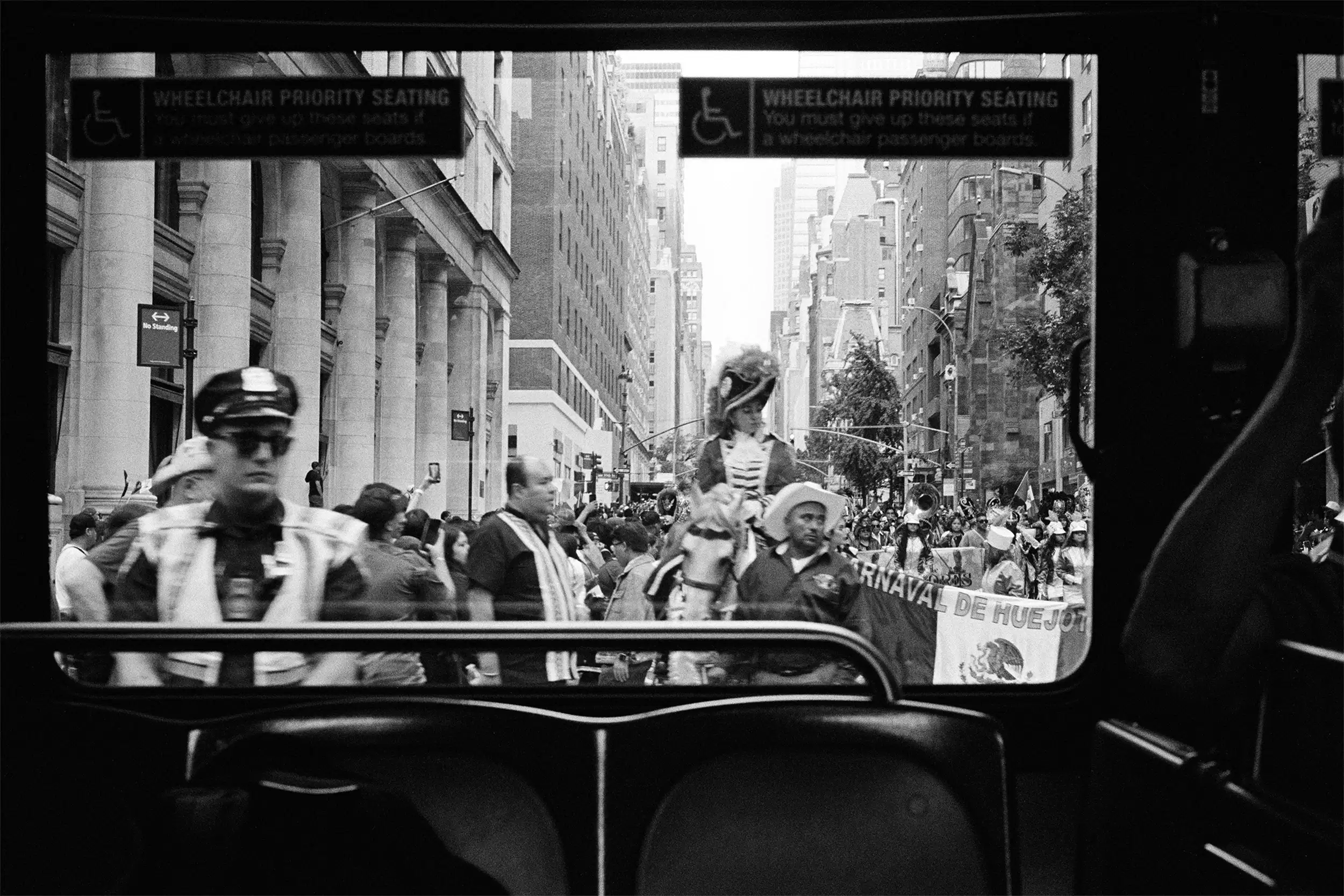 A photo captures the 2023 Hispanic Day Parade on NYC's Fifth Ave, viewed from a bus window.