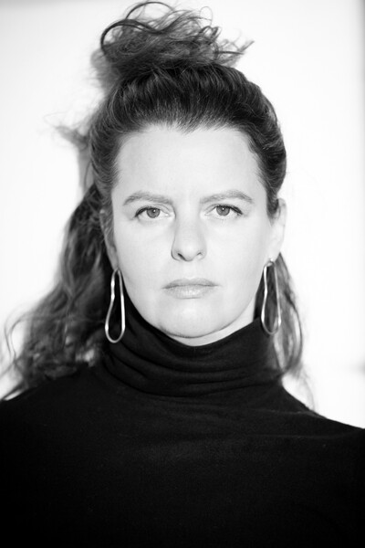 Faculty member Ksenya Samarkaya wearing a black turltleneck and long silver earrings.