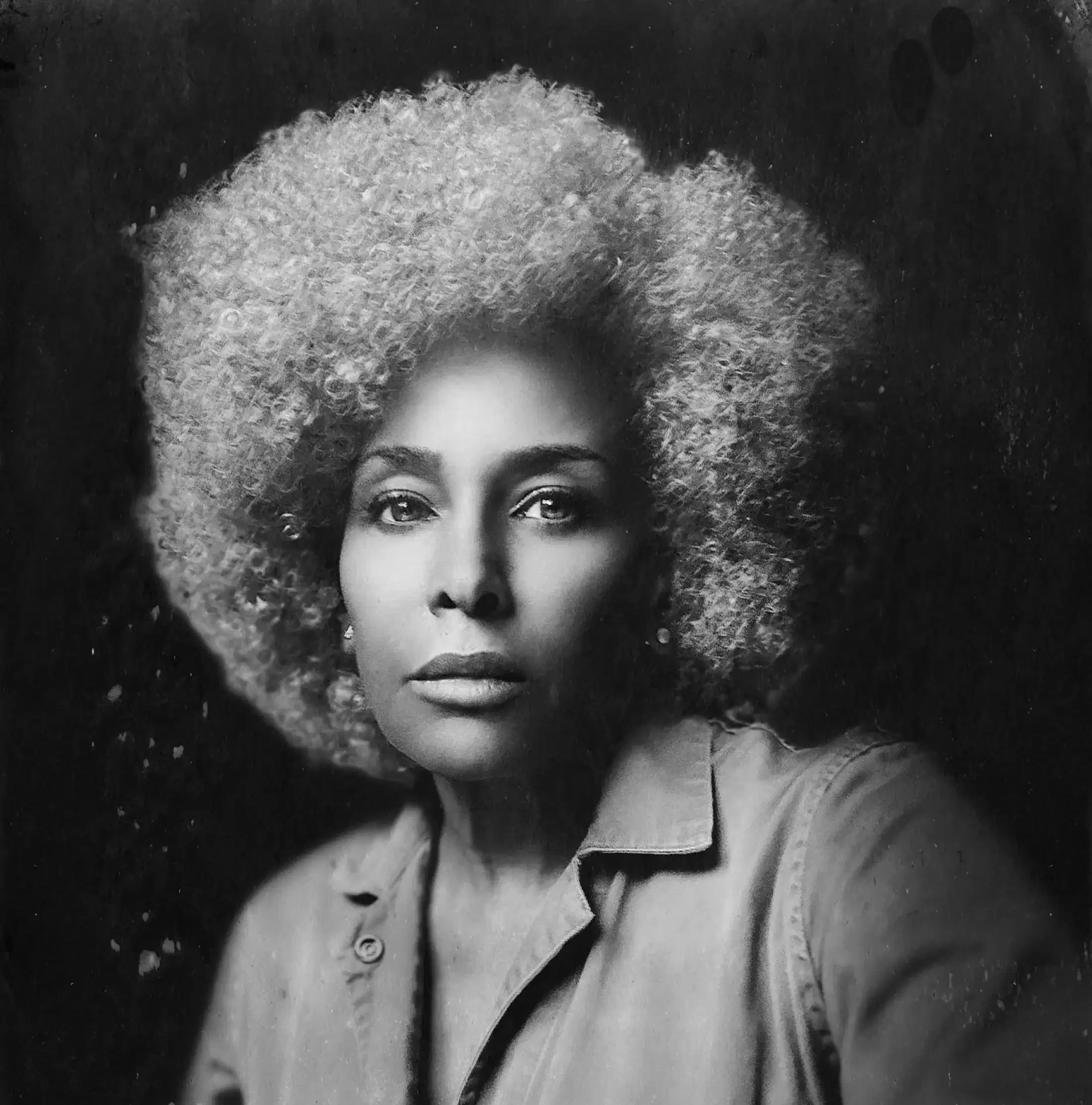 Black and white photographic portrait of a person against a non-uniform black background