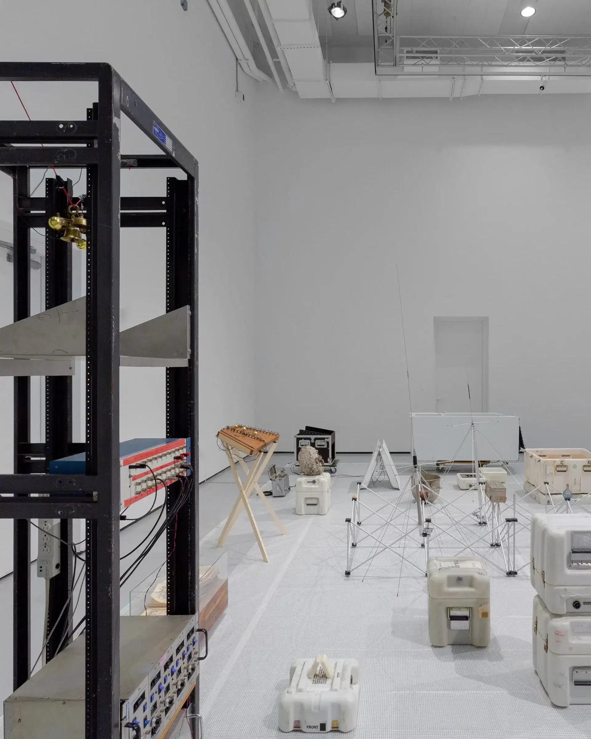 Installation by Stephen Lordan. The image shows various objects laid out on the floor in light grey room.