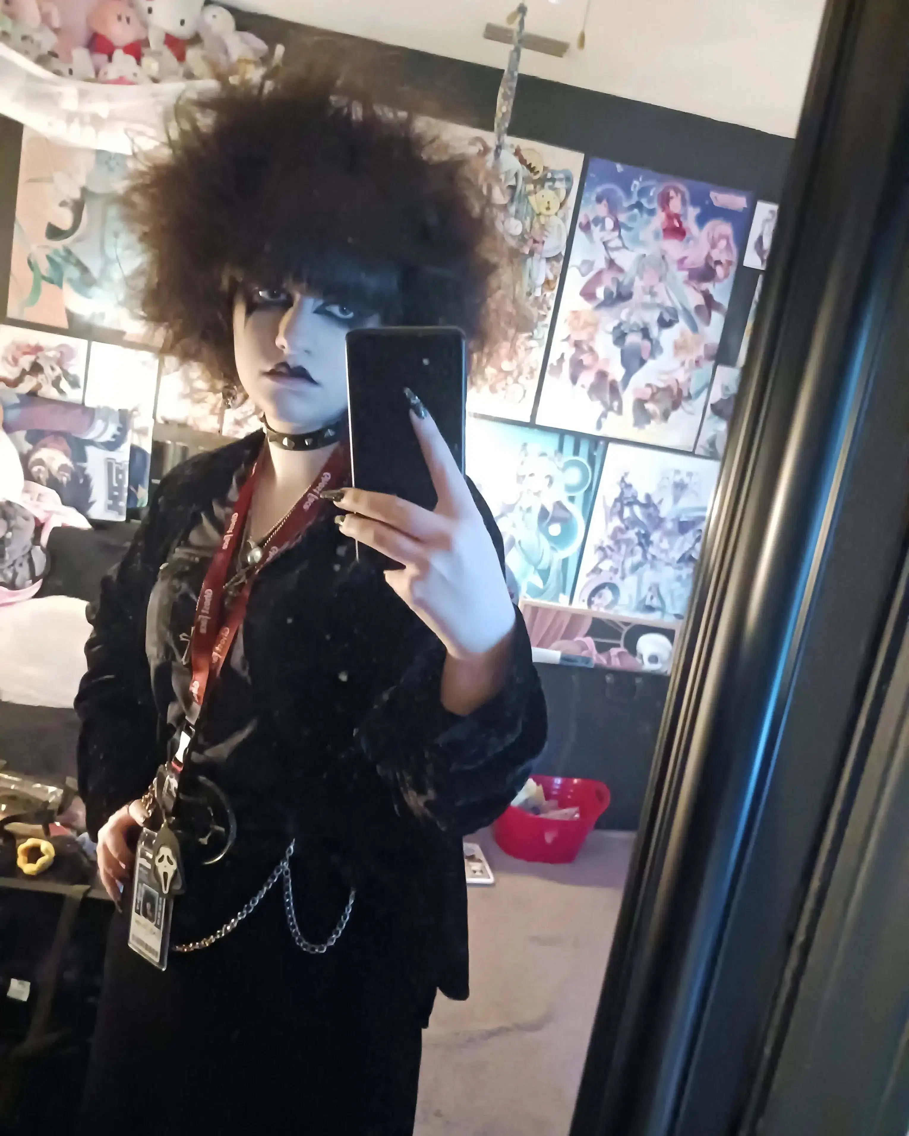An individual dressed in alternative, punk/goth clothing takes a mirror selfie.