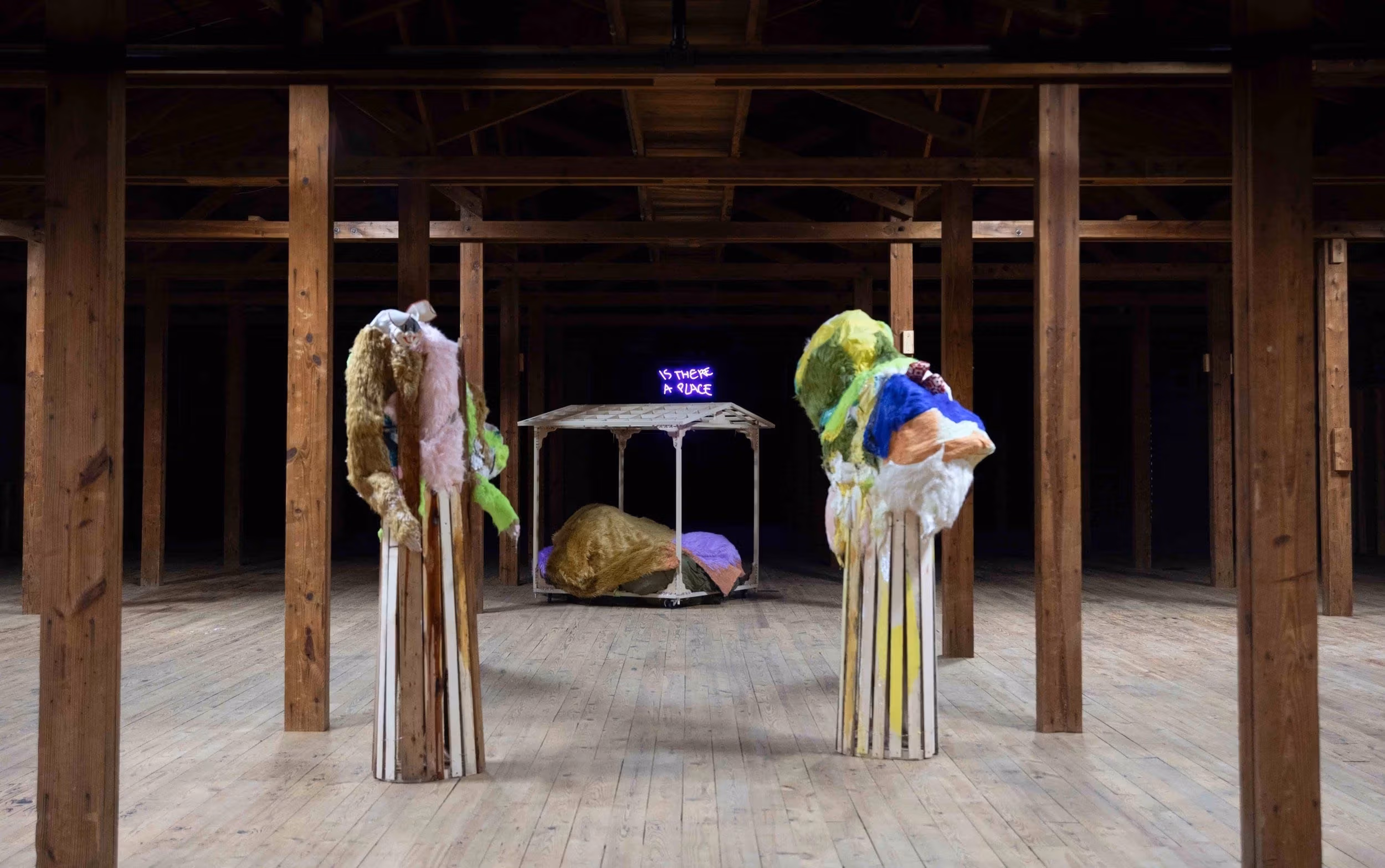  A room featuring wooden poles and various sculptures arranged on the floor, showcasing an artistic and natural ambiance.