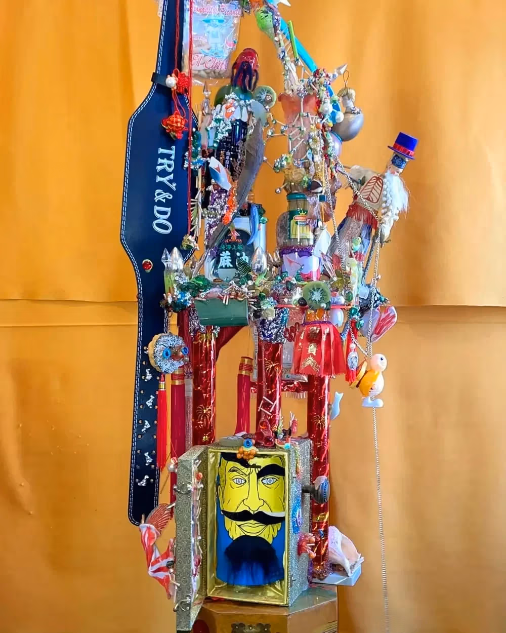A colorful sculpture made up of found objects relating to Chinese culture.