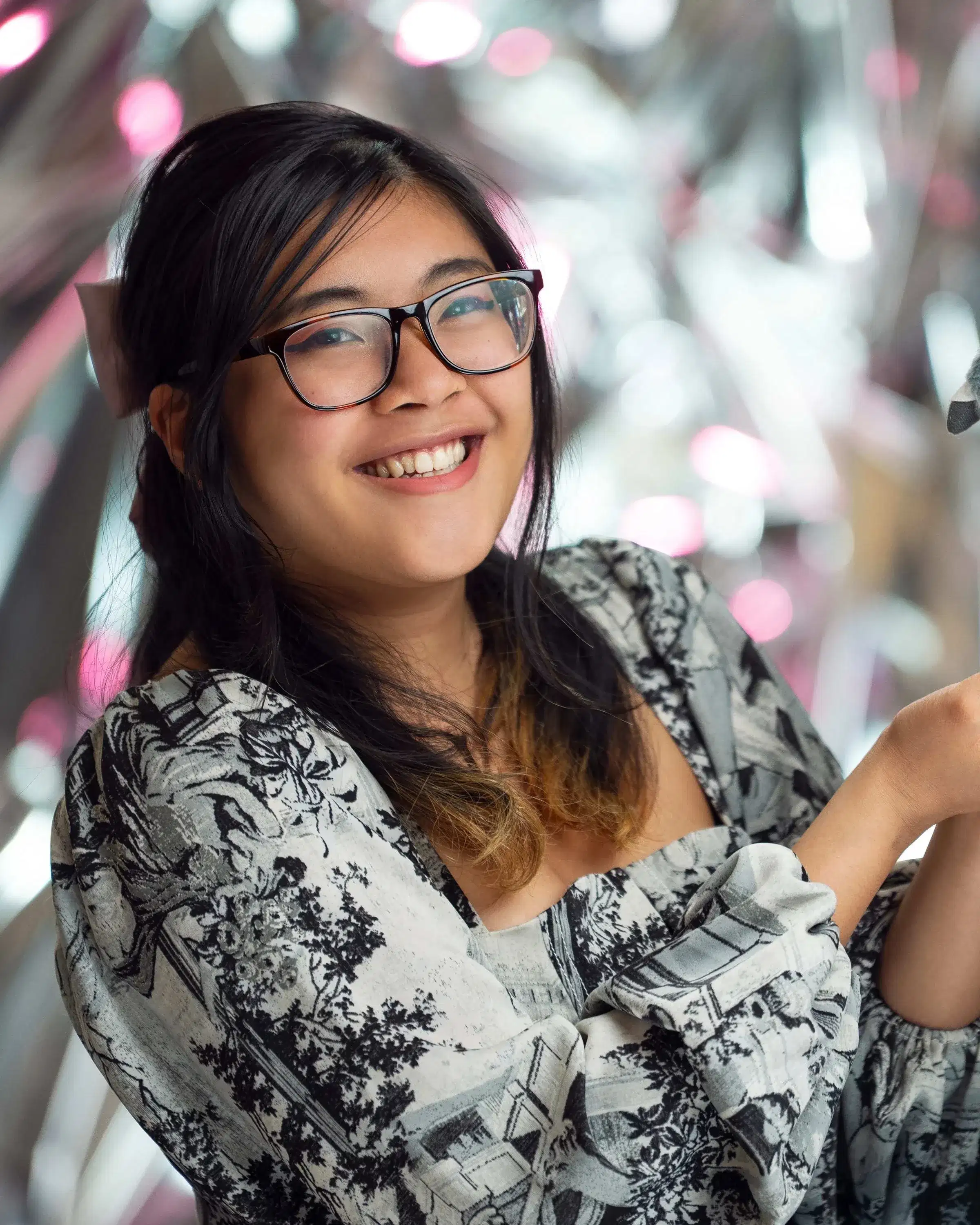 A girl with glasses and a bow in her hair holds a pigeon plus and smiles at the camera.
