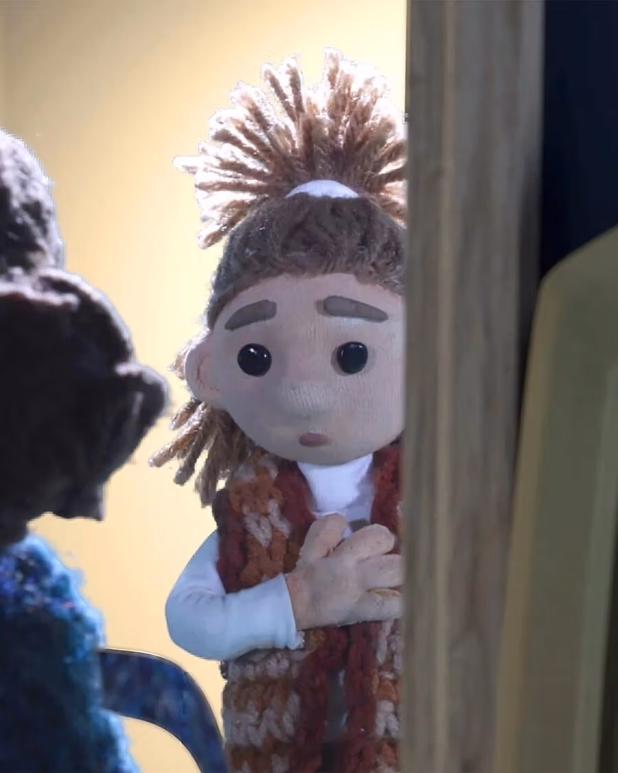  Backlit, a little girl peers into a dark room speaking to another girl.