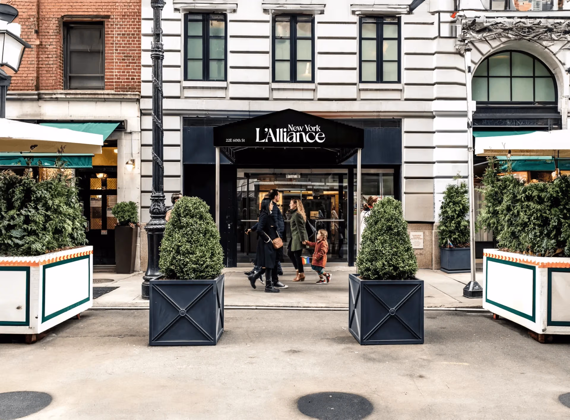A large awning with the lettering New York L’Alliance while people walk by Photo Credit: L’Alliance New York