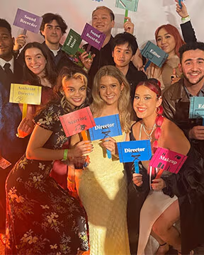  Photo of BFA Film students standing together in front of a step and repeat at the BFA Film thesis showcase