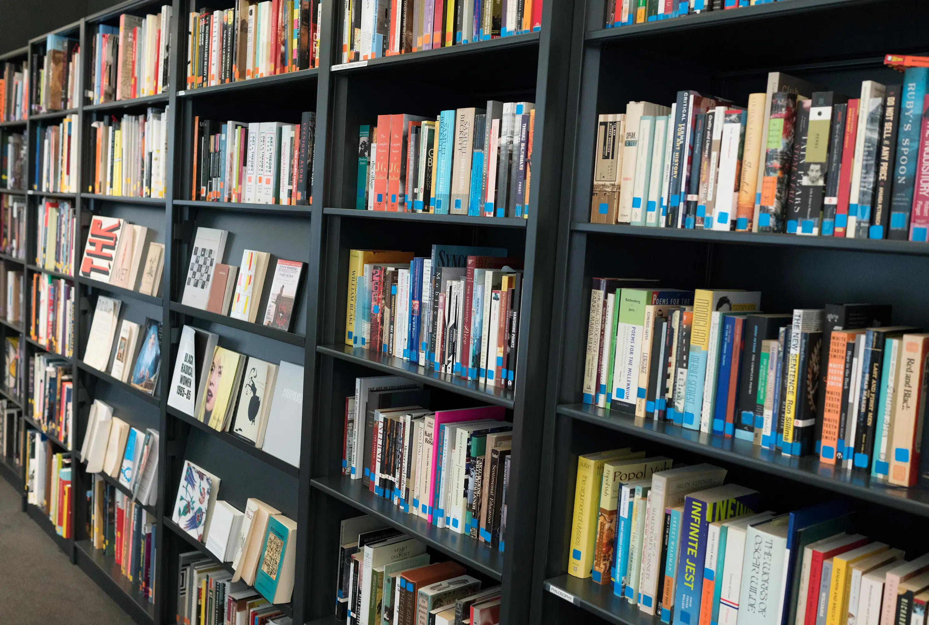 Stacks of library books in a black bookshelf.