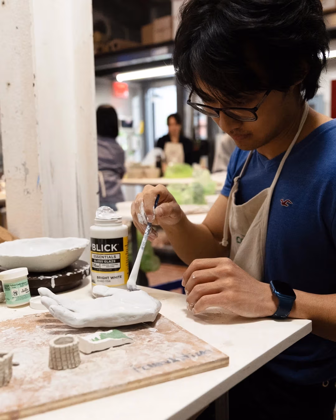 student glazing a ceramic hand
