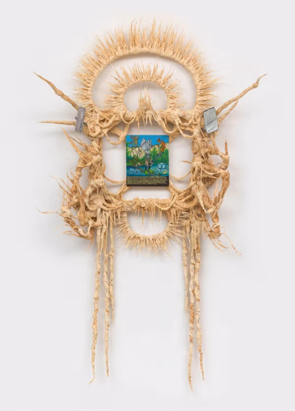 A small oil painting framed by a sculpture reminiscent of a headdress.