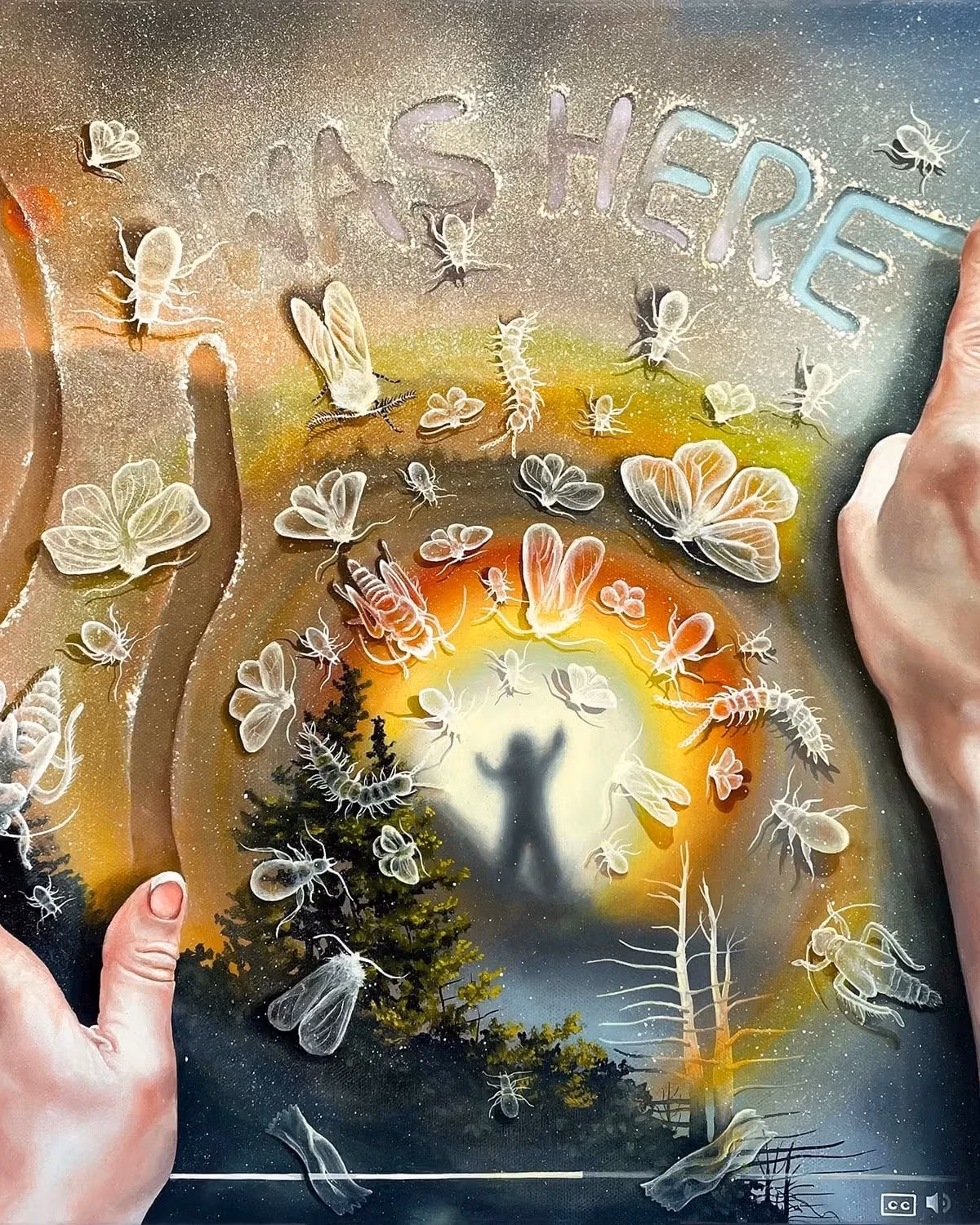 Two hands rest atop a surface, the left drawing vertical lines with their fingers, the right pointing creating the words "I Was Here" out of a sandy texture. Below this semi-transparent texture is a forested landscape with a figure standing atop a mountain as a rainbow radiates around them.