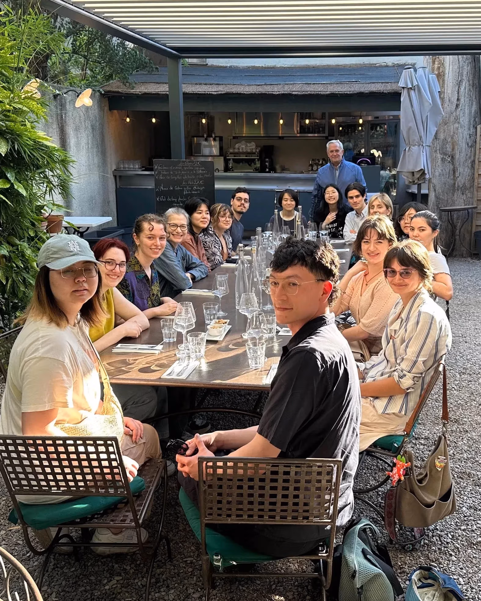 A group of people at a dinner table smile and look at the camera. 