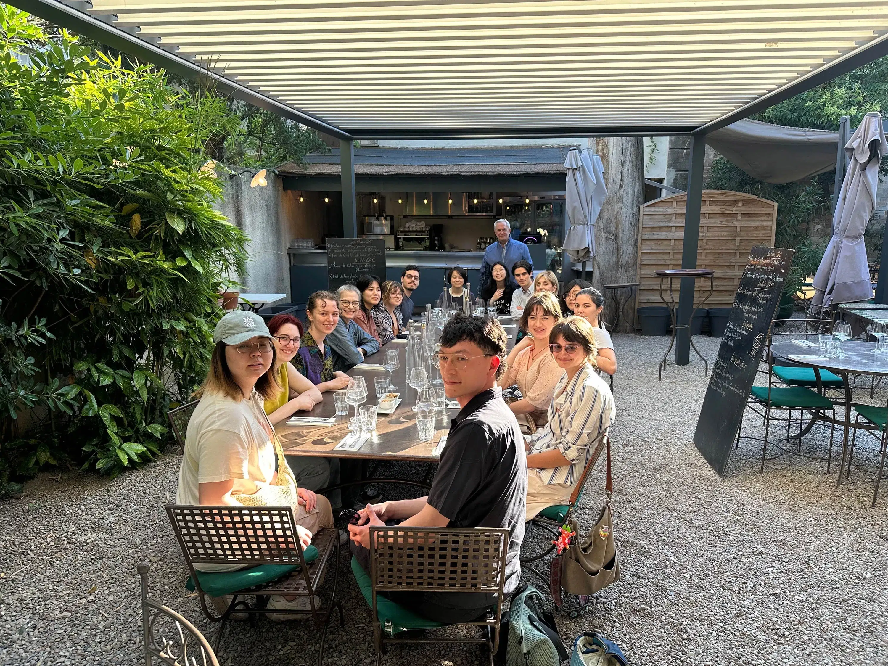 A group of people at a dinner table smile and look at the camera. 