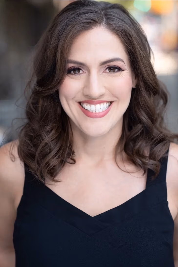 A photo of a woman from the shoulders up. She has long brown hair and is smiling.