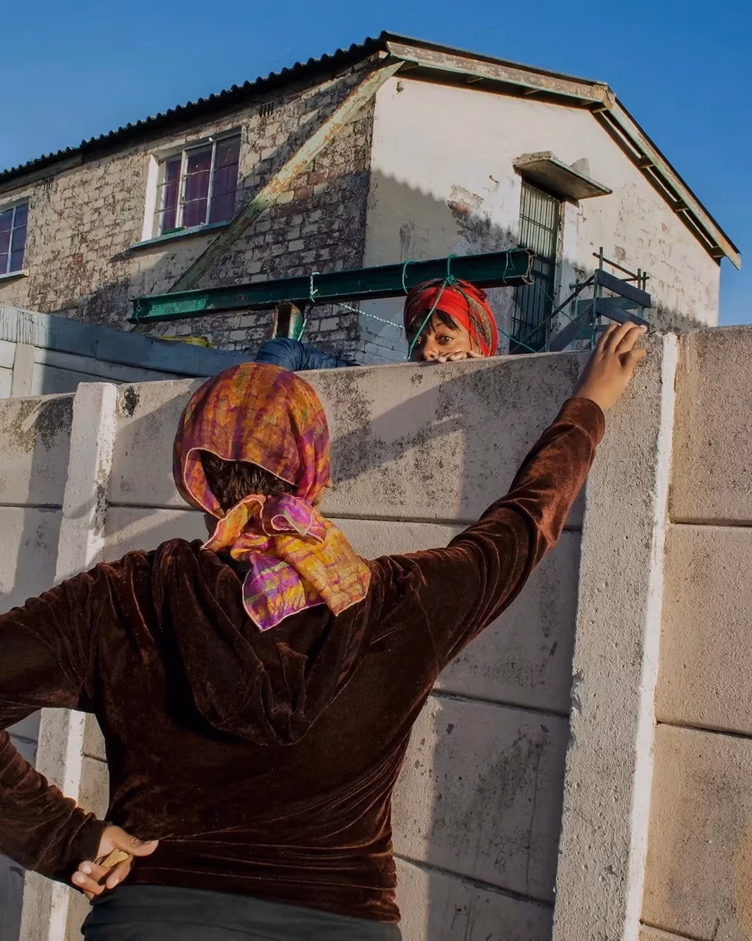 Two women speaking over a concrete wall. 