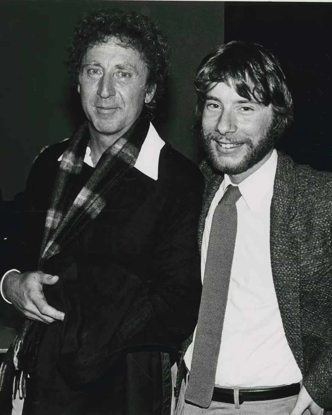 A black and white photo of two people posing and smiling next to each other.