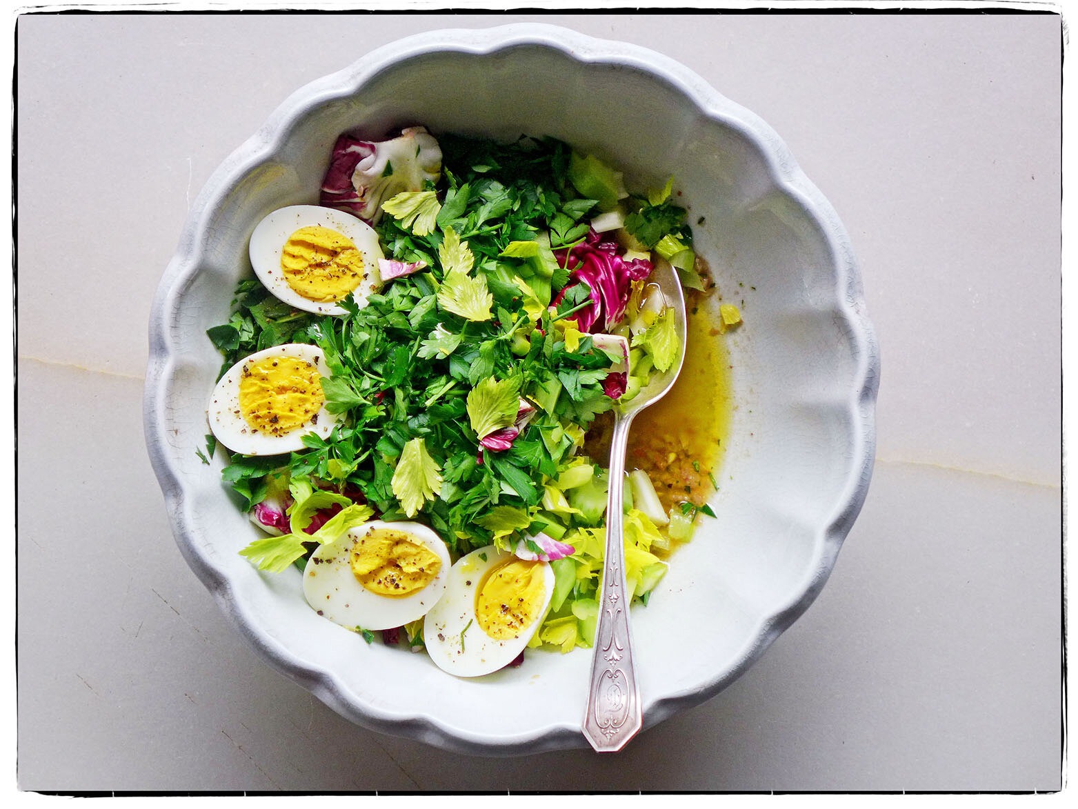 A color photograph of a salad with several halves of hard-boiled eggs.