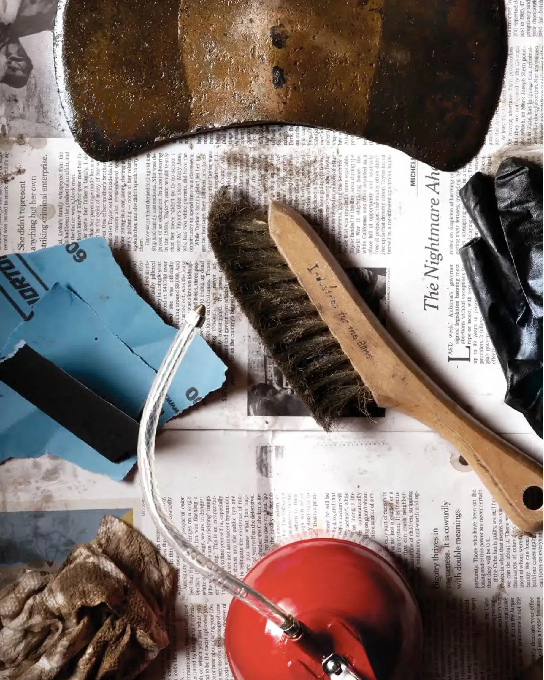 A collection of tools and miscellaneous items arranged on top of a newspaper, showcasing a cluttered workspace.