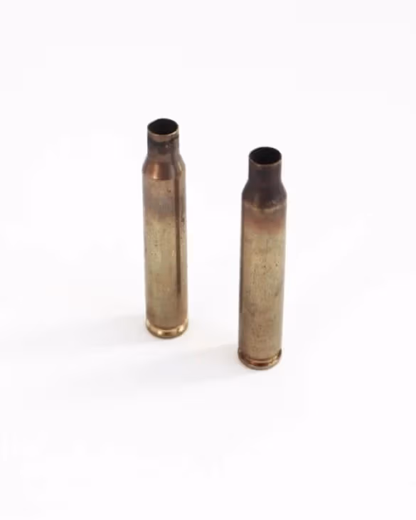 Two bullet casings standing upright on a white surface.