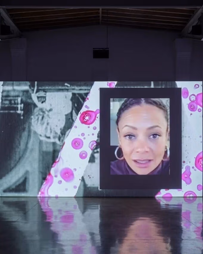 Projected screen depicting a woman's face as well as other shapes and images in the composition around her. 