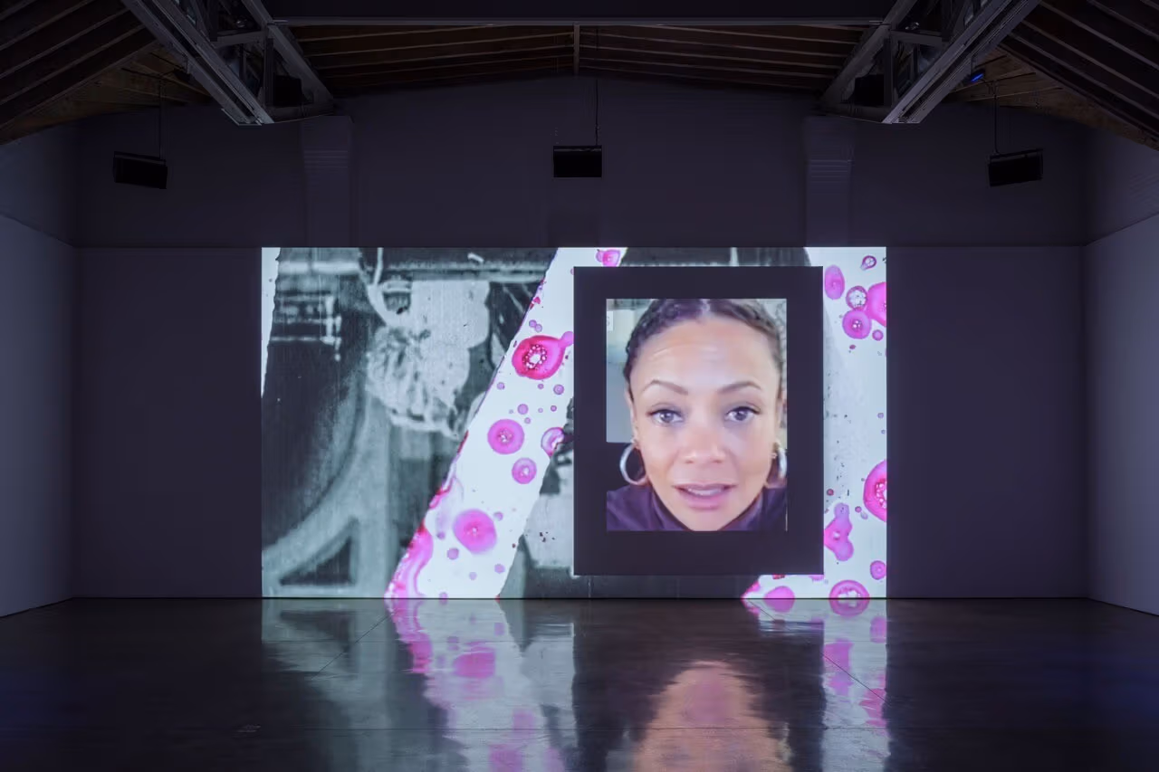 Projected screen depicting a woman's face as well as other shapes and images in the composition around her. 
