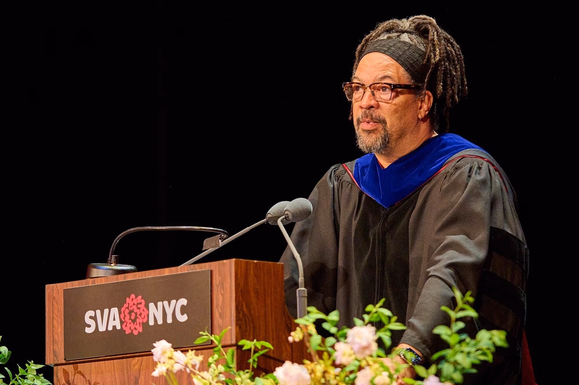 Commencement speaker Gary Simmons speaking on a podium decorated with flowers and the SVA logo