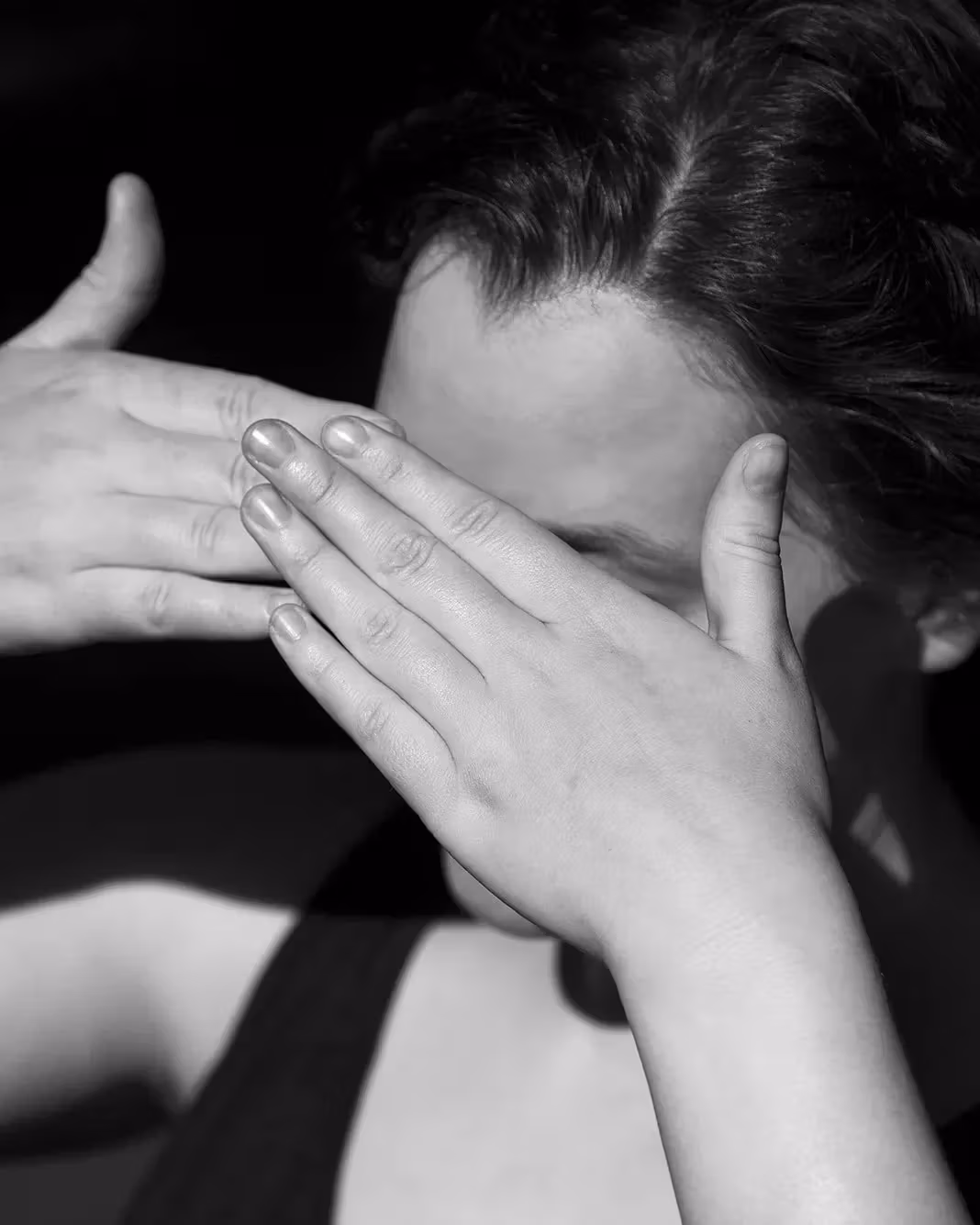 A photograph of an individual covering their eyes as if the sun was shining into them. 