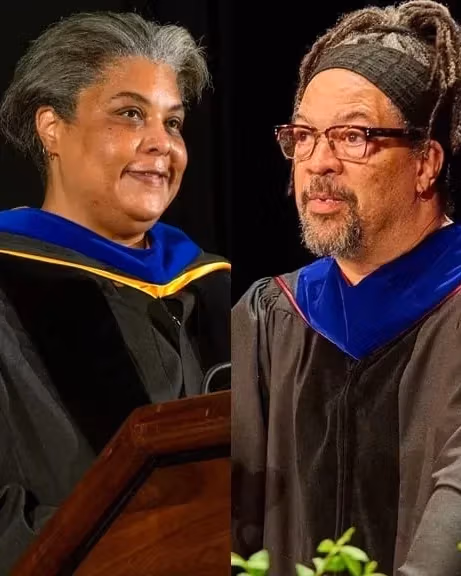 Four graduate speakers in caps and gowns stand at podiums during a graduation ceremony, celebrating their academic achievements.