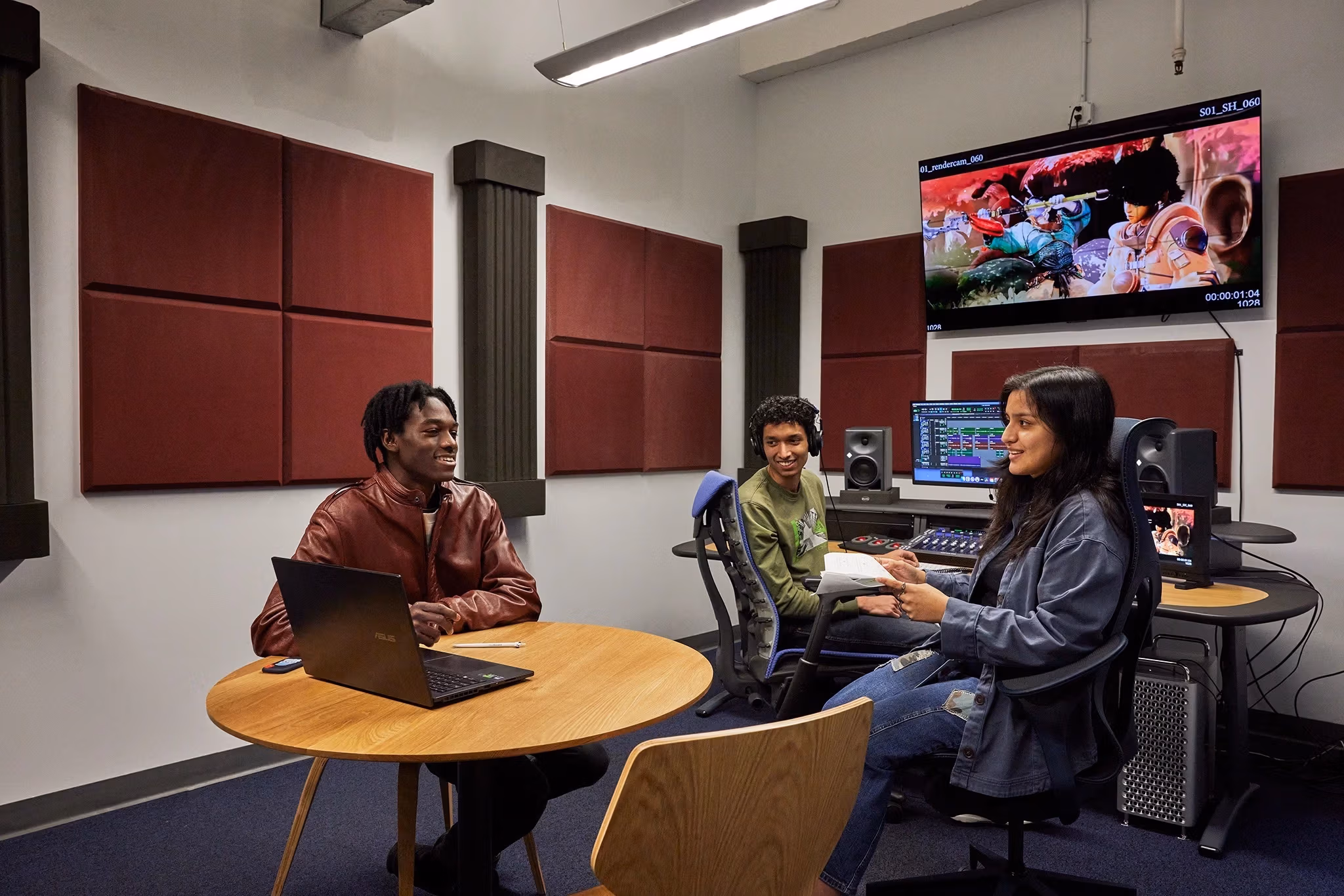 three people in front of an audio mixing board and display