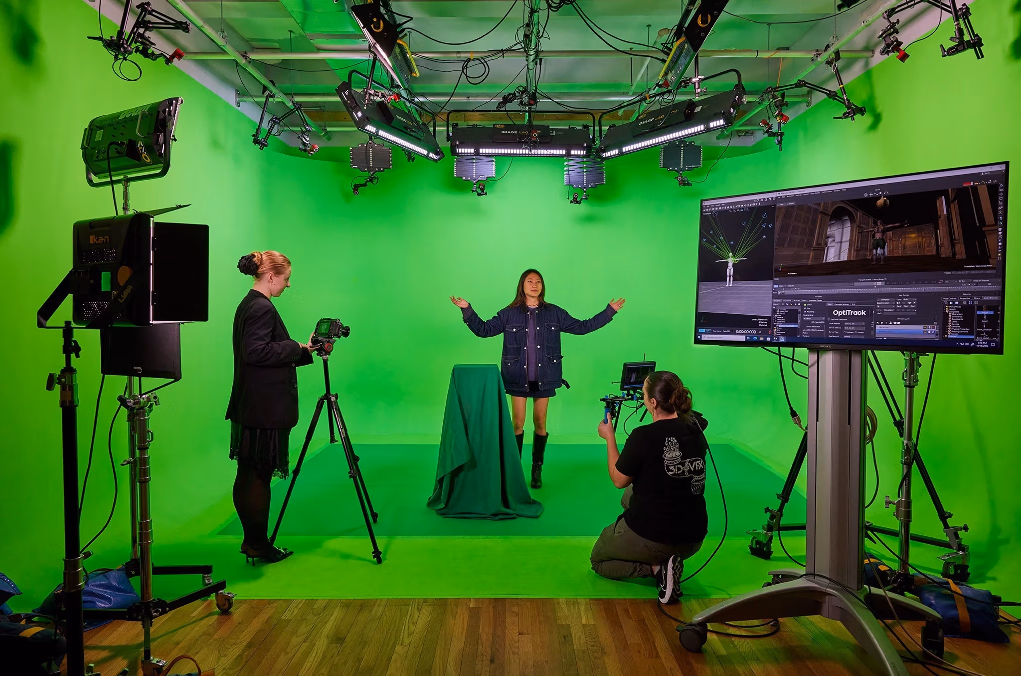 three people in front of a green screen with cameras and motion capture equipment