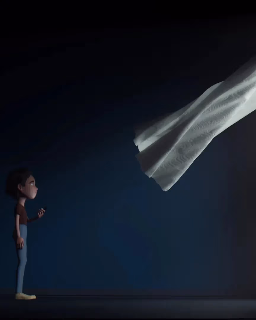 A student stands in a dark empty room with a window. They're looking out the window while the curtain billows into the room.